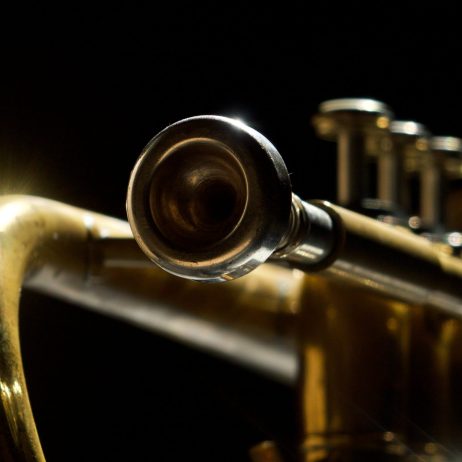 Kuvassa pronssinen trumpetti mustalla taustalla